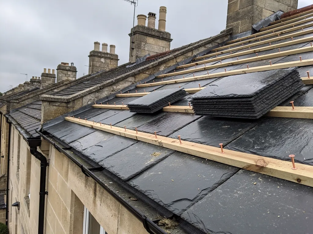 Natural Welsh slates being nailed to battens on a Bath terrace roof